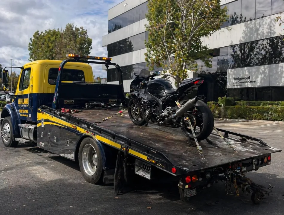 motorbike towed on flatbed tow truck during the day from office parking lot in oakland, ca